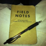 Photo of a worn Field Notes notebook with a black pen